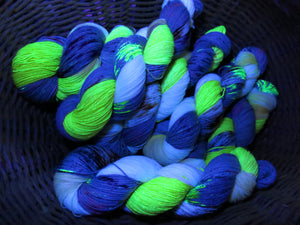 hand dyed uv reactive yarn skeins glowing under black light