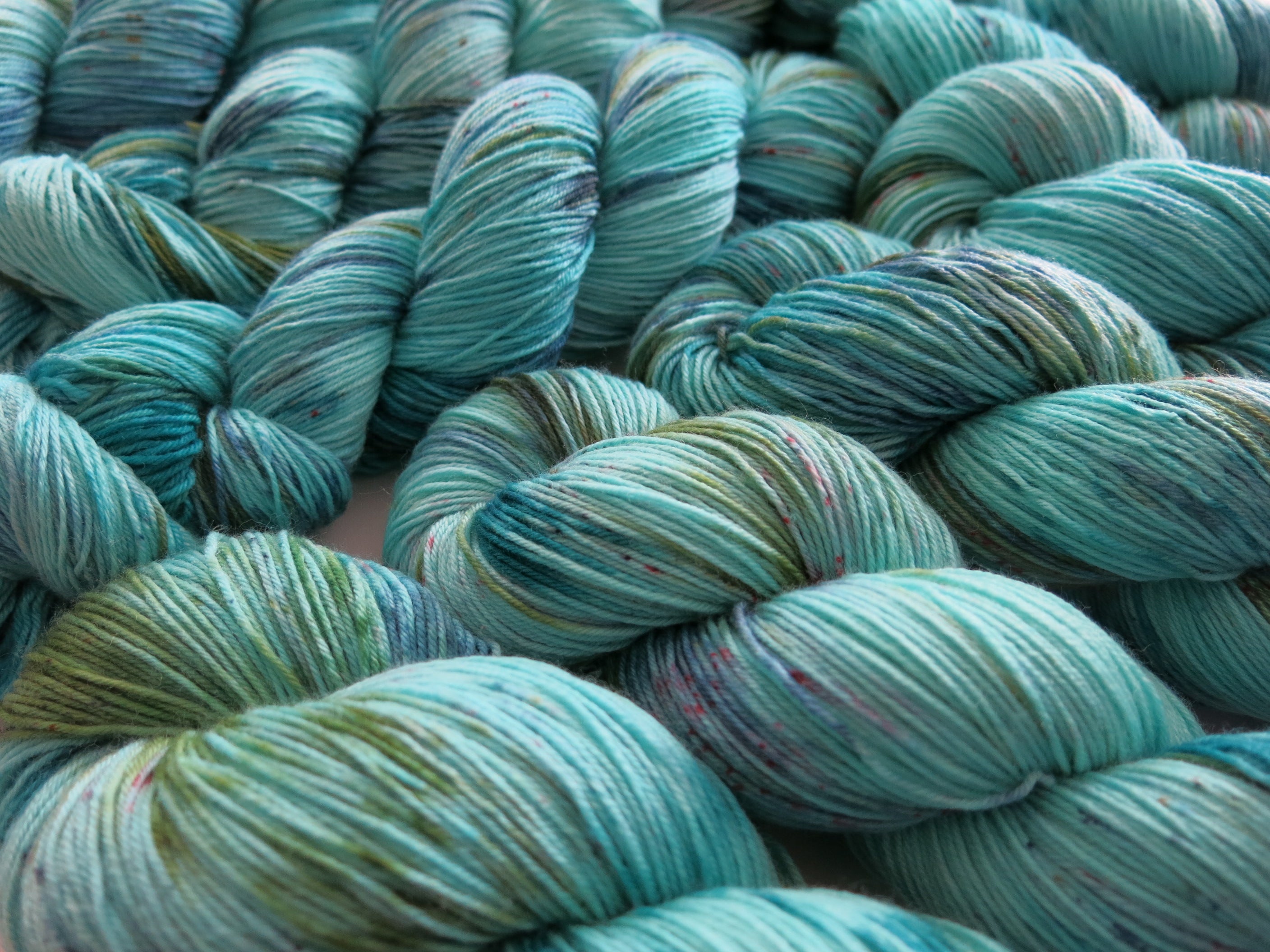 indie dyed speckled blue and green superwash merino sock yarn skeins