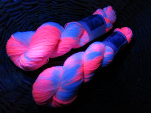 pink and white yarn skeins glowing under uv black lights