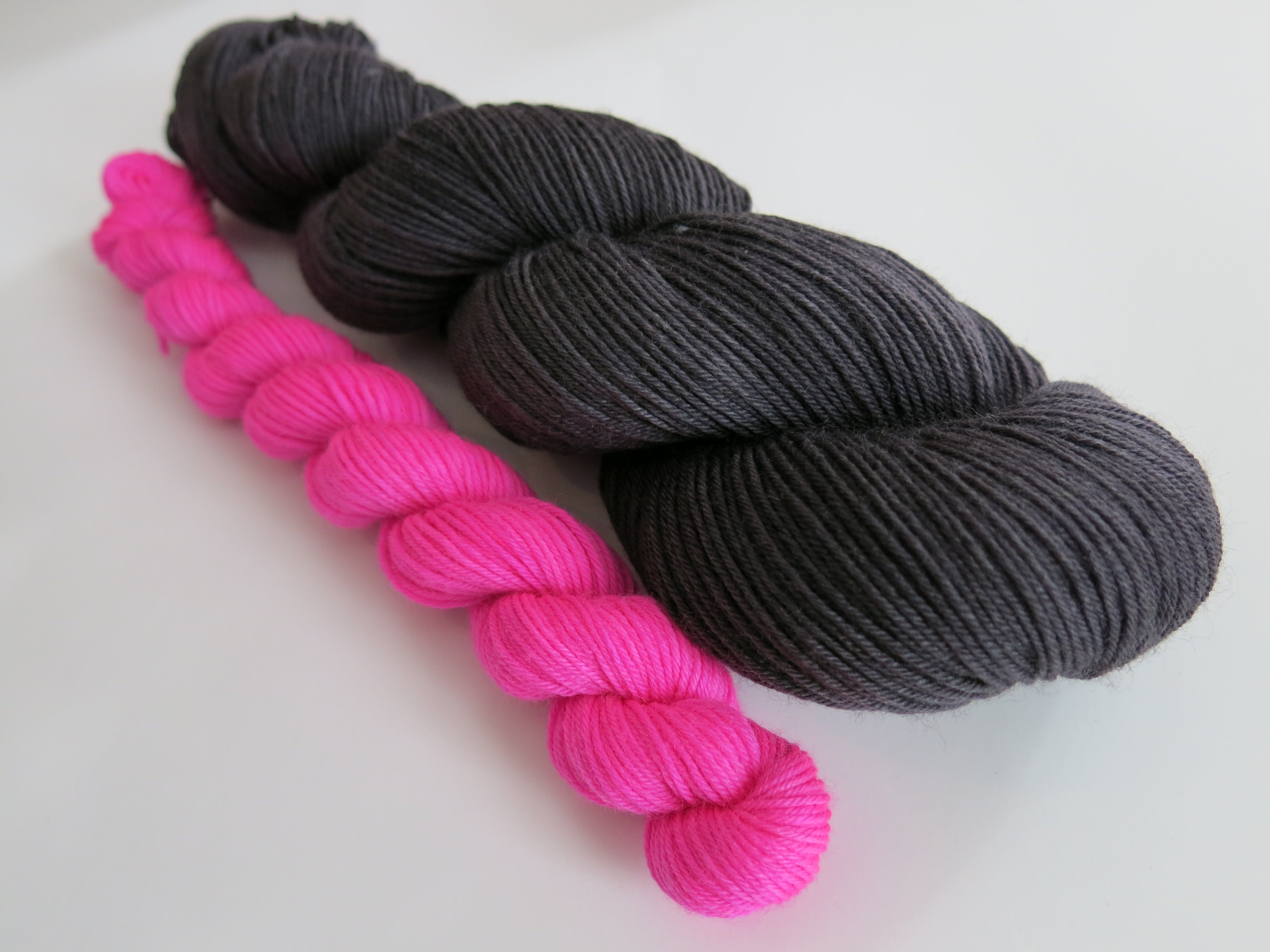 hand dyed black yarn with a neon pink mini skein