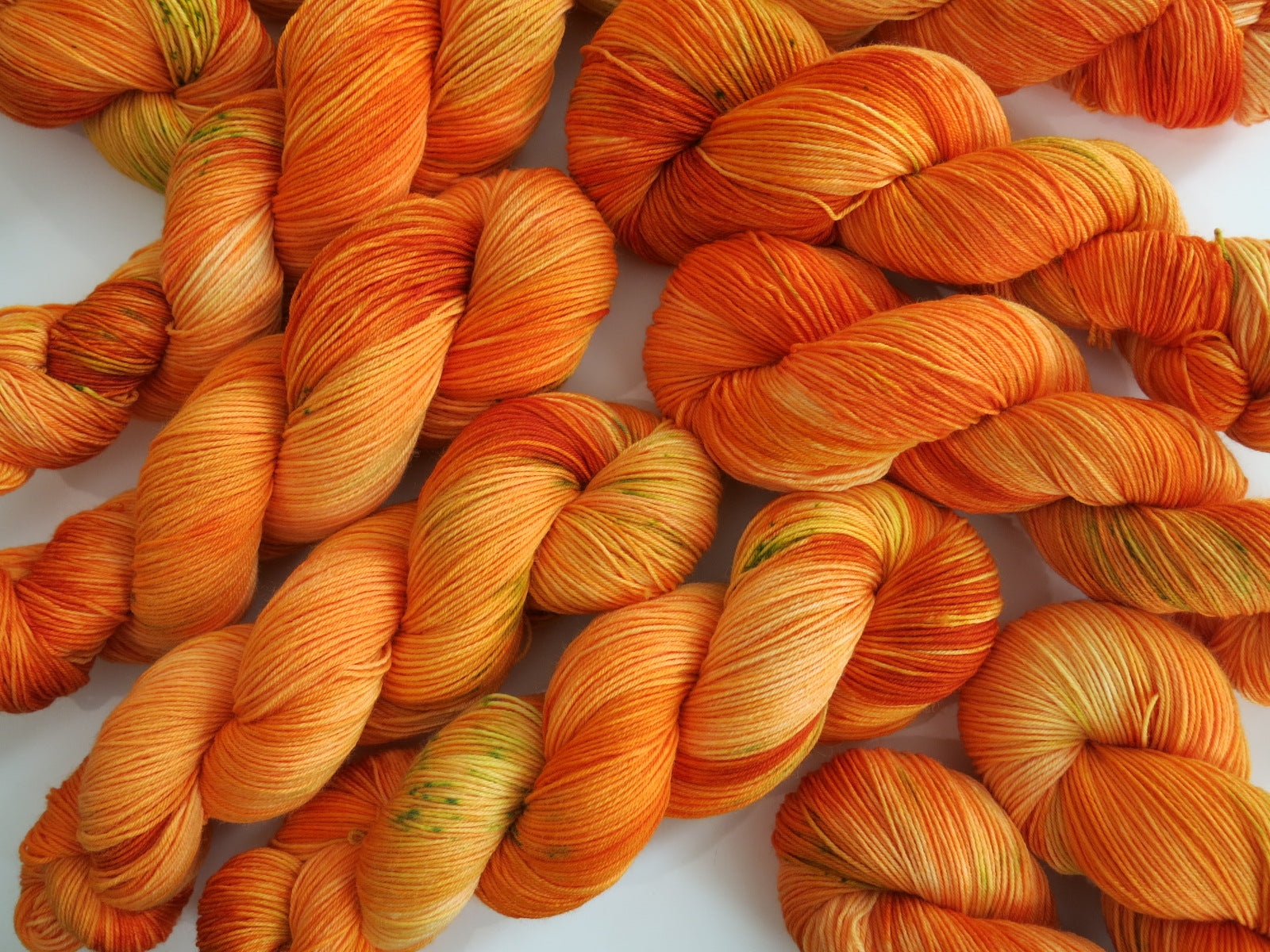 uv reactive orange sock yarn skeins with green speckles