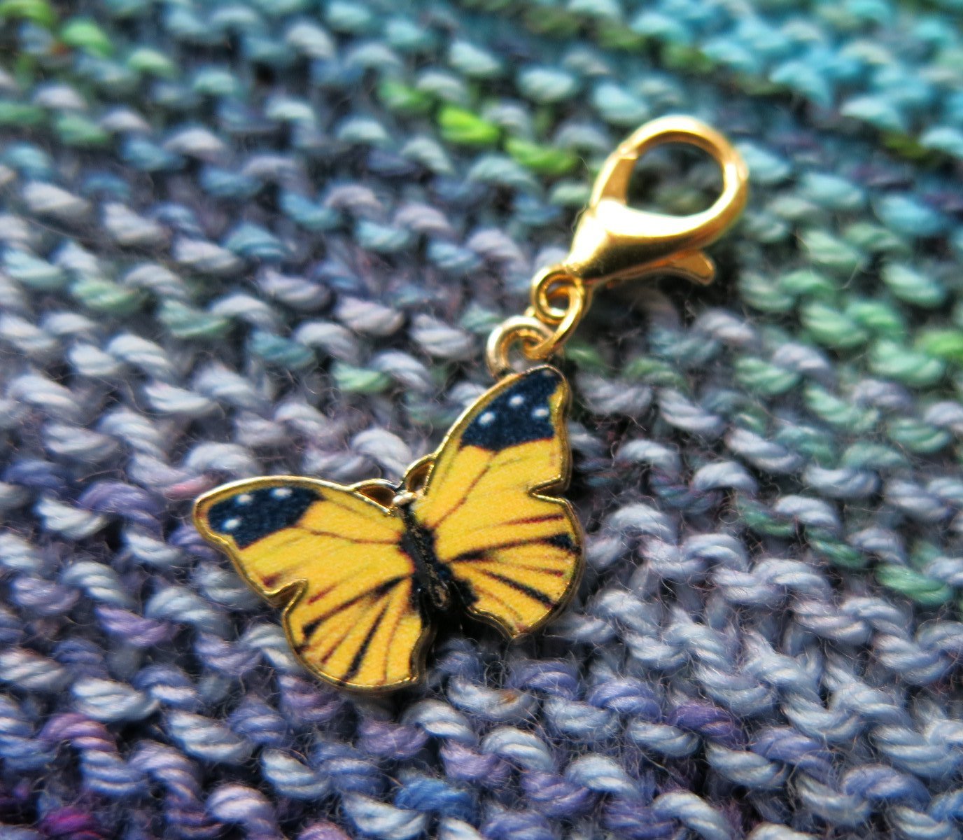 yellow enamel butterfly charm on a gold coloured lobster clasp