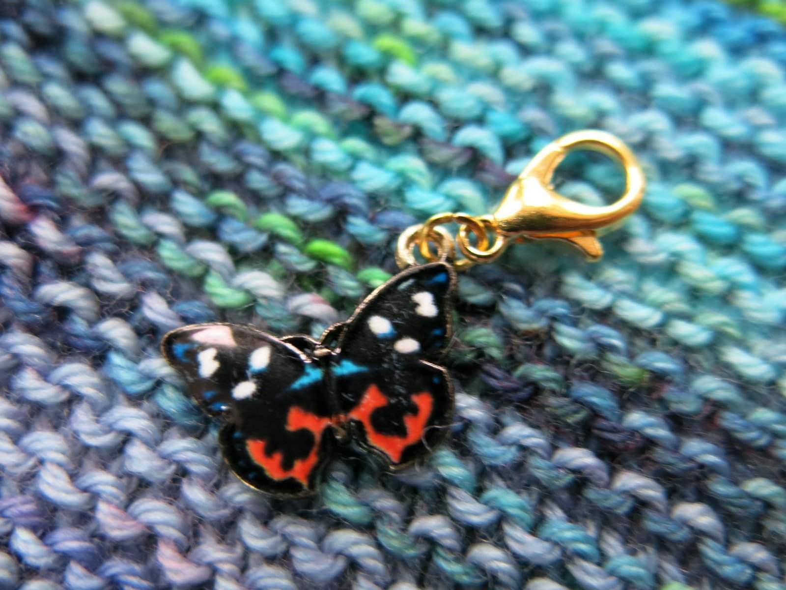 orange and black enamel butterfly charm on a gold coloured lobster clasp