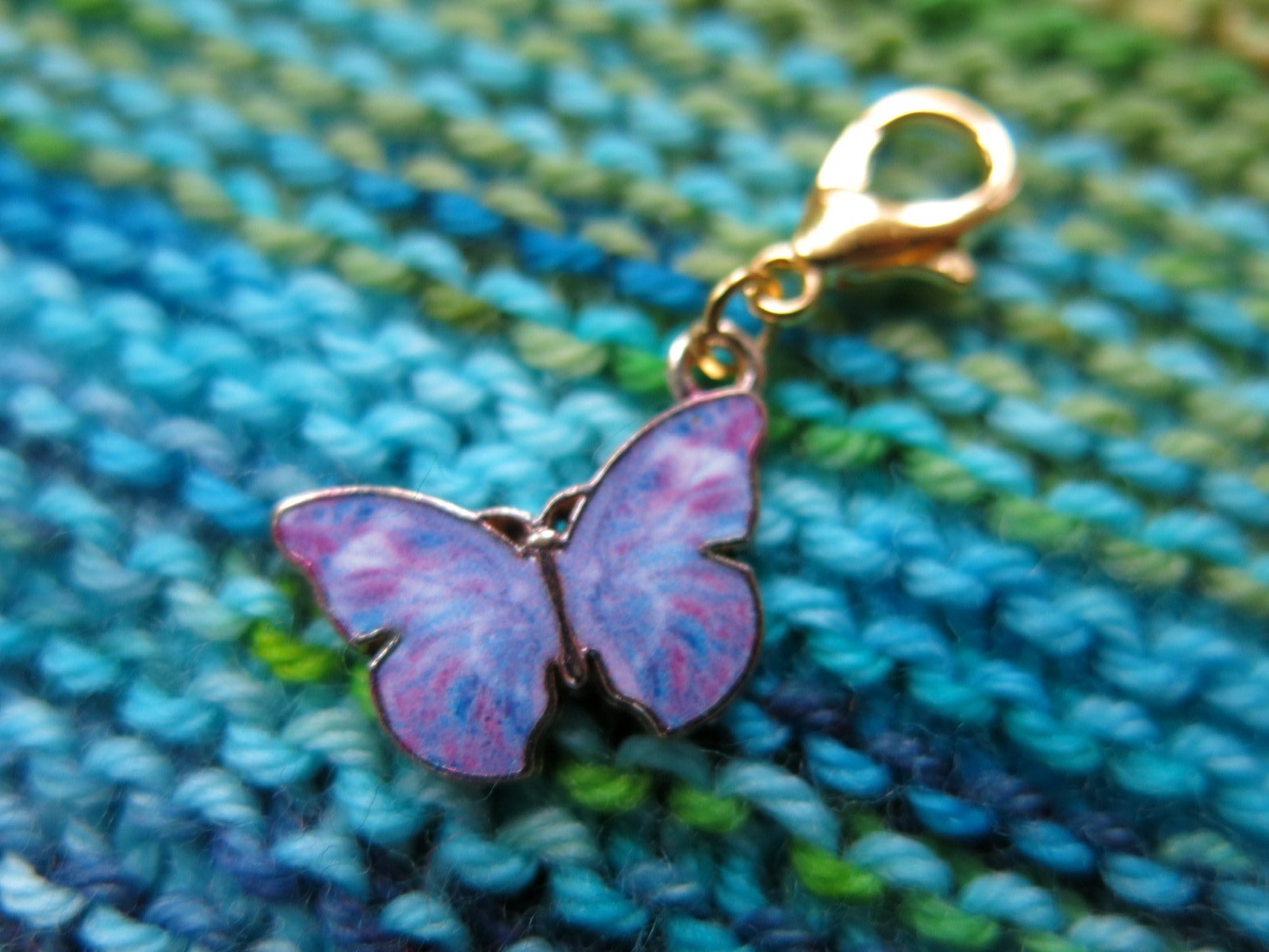purple enamel butterfly charm on a gold coloured lobster clasp