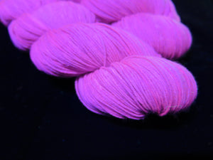 hand dyed solid purple yarn fluorescing under uv black light