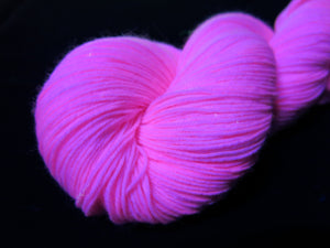 hand dyed solid light pink yarn fluorescing under uv black light