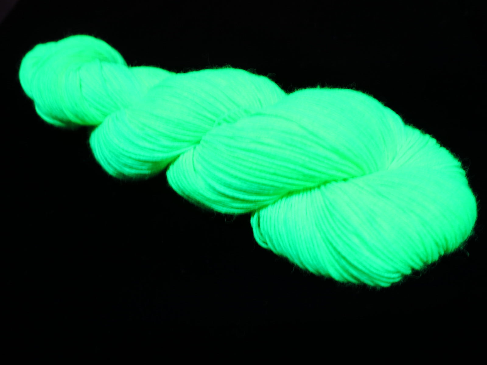 green uv reactive knitting yarn glowing under fluorescent blacklight