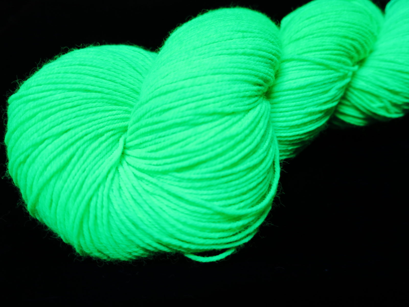 hand dyed bright neon green yarn fluorescing under uv black light