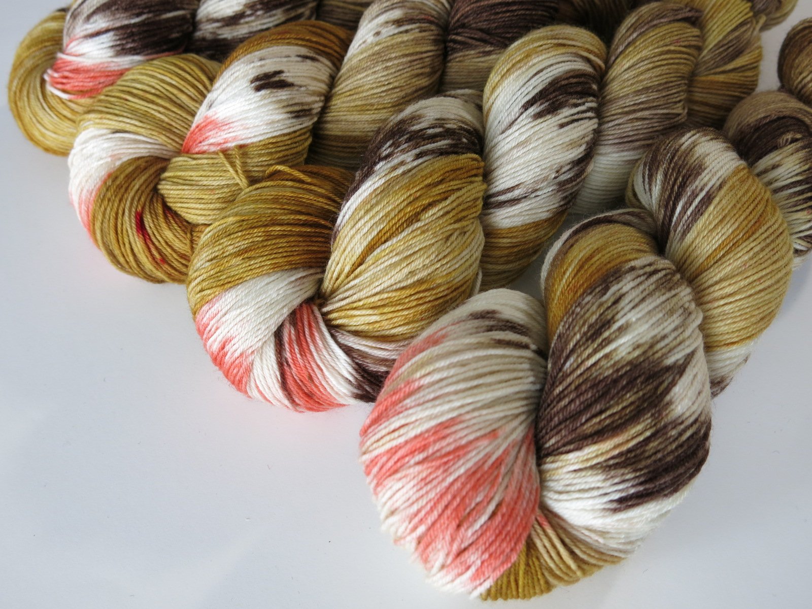 hand dyed yarn skeins in tan and brown with a pop of coral