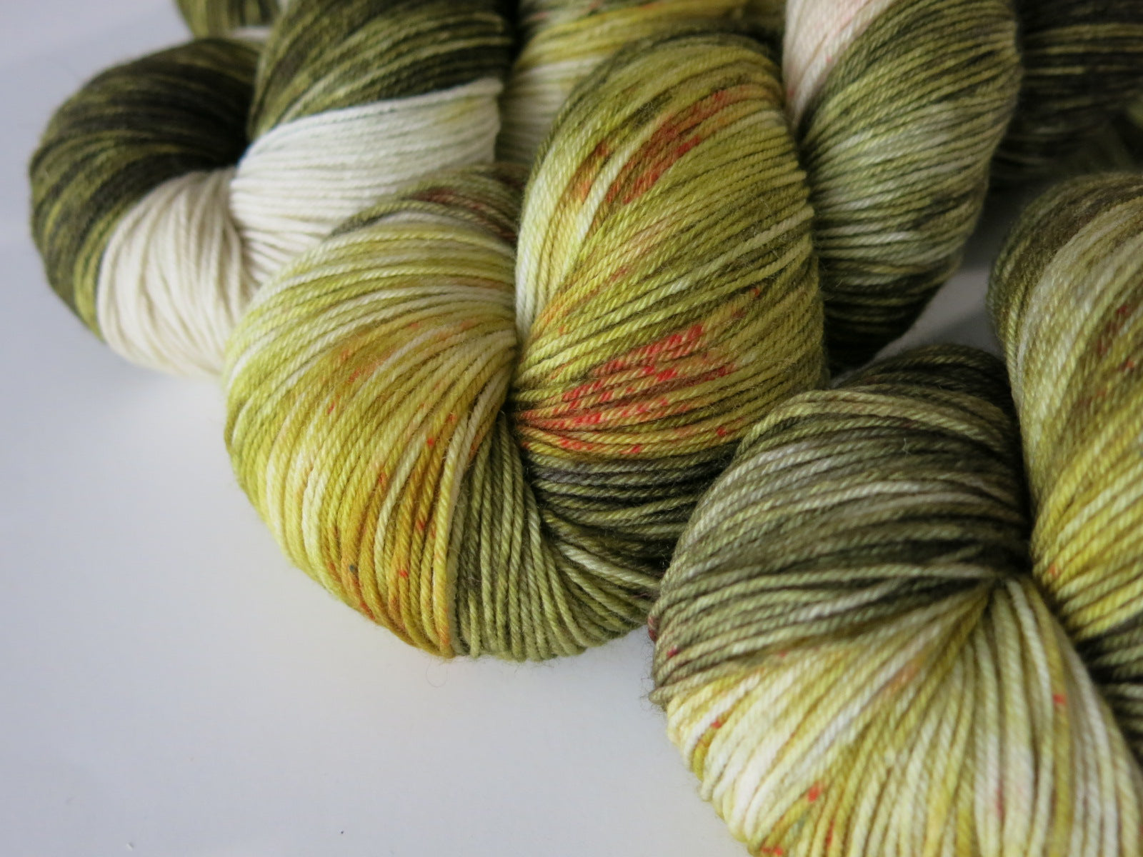 green and cream 4 ply sock yarn with red speckles like a trex