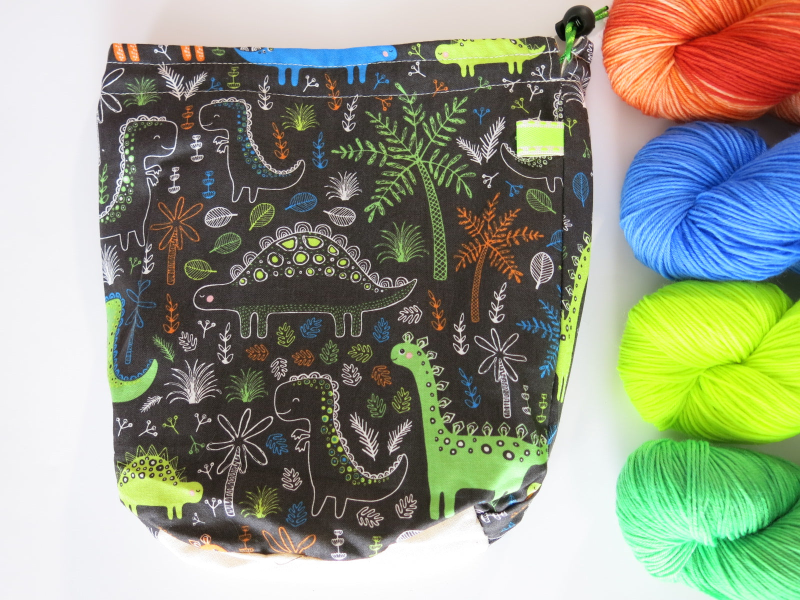 cotton drawstring knitting project bags with cartoon dinosaurs with a brown background