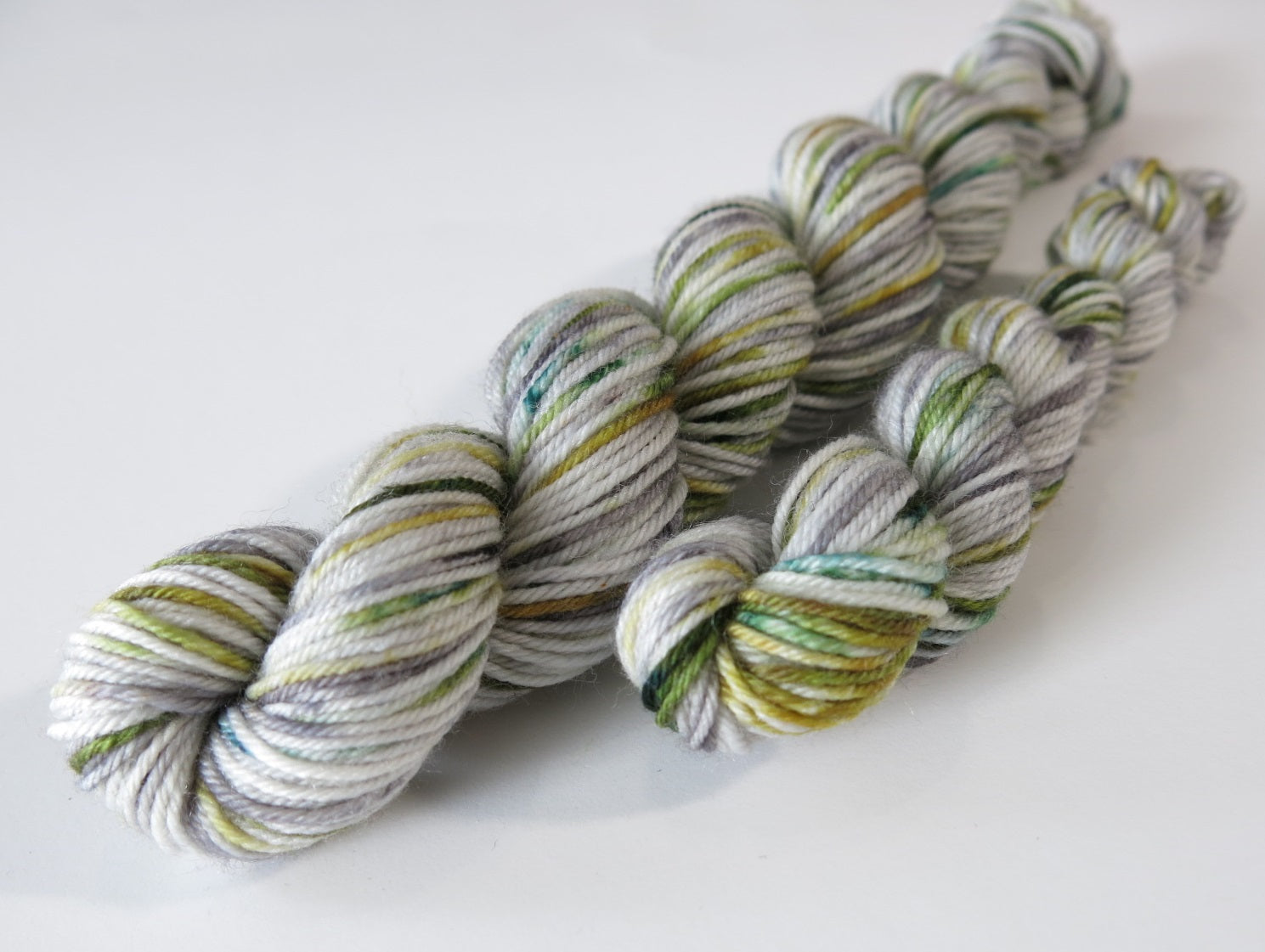 light and dark grey yarn mini skein with green speckles