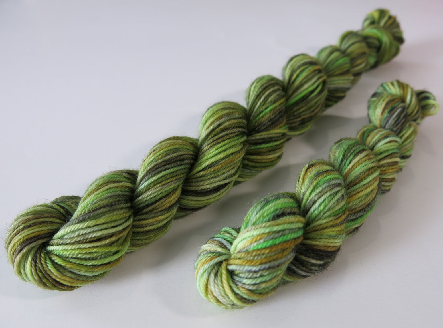 hand dyed sock yarn mini skein with multiple bright to mossy greens