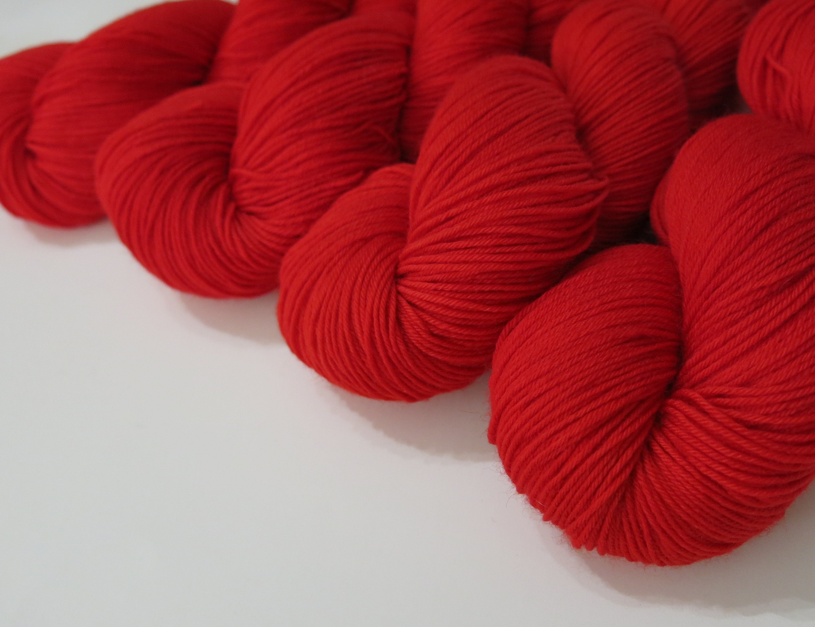 magic ribbon hand dyed solid red superwash merino sock yarn skeins