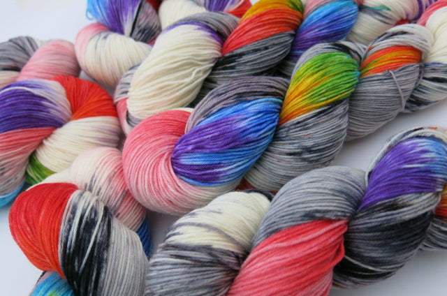 sock yarn skeins with rainbow colours and grey speckles on white and grey