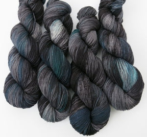 grey and black yarn skein with areas of teal and blue