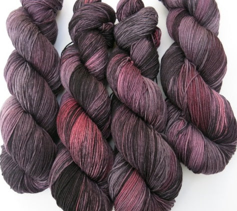 grey and black yarn skein with areas of red and pink