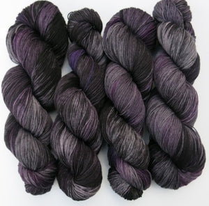 grey and black yarn skein with areas of plum purple