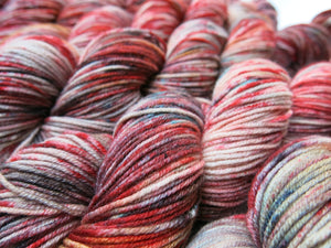 red and blue speckled 8 ply merino yarn skeins